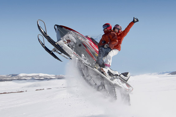 two people in winter attire on a jet ski in the snow