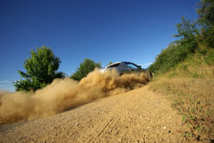 truck driving down dirt road with large dust trail