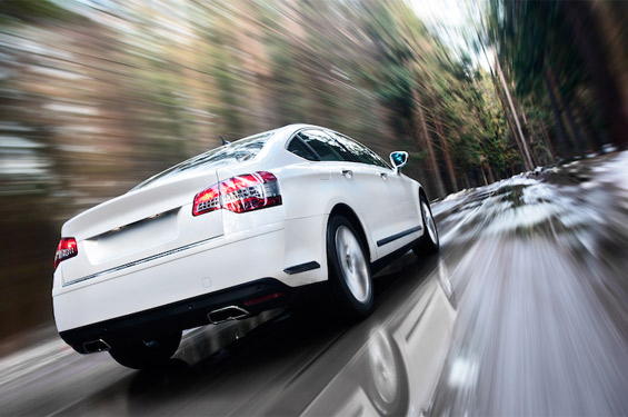 white car driving down road - background slightly blurred
